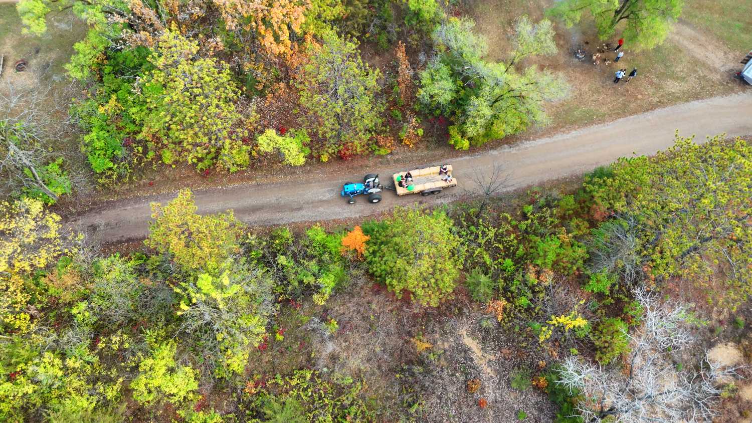 A tractor pulls a trailer for a haybale ride, with kids on the back.